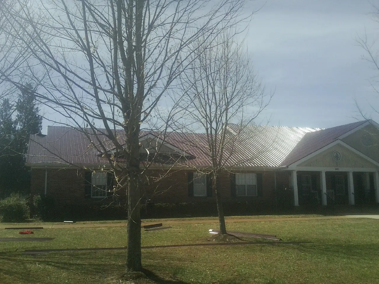 Red metal roof on a brick building seen from the front lawn in Huron
